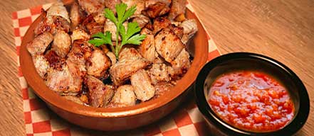 tapa de cerdo frito acompañado de salsa de pimientos rojos